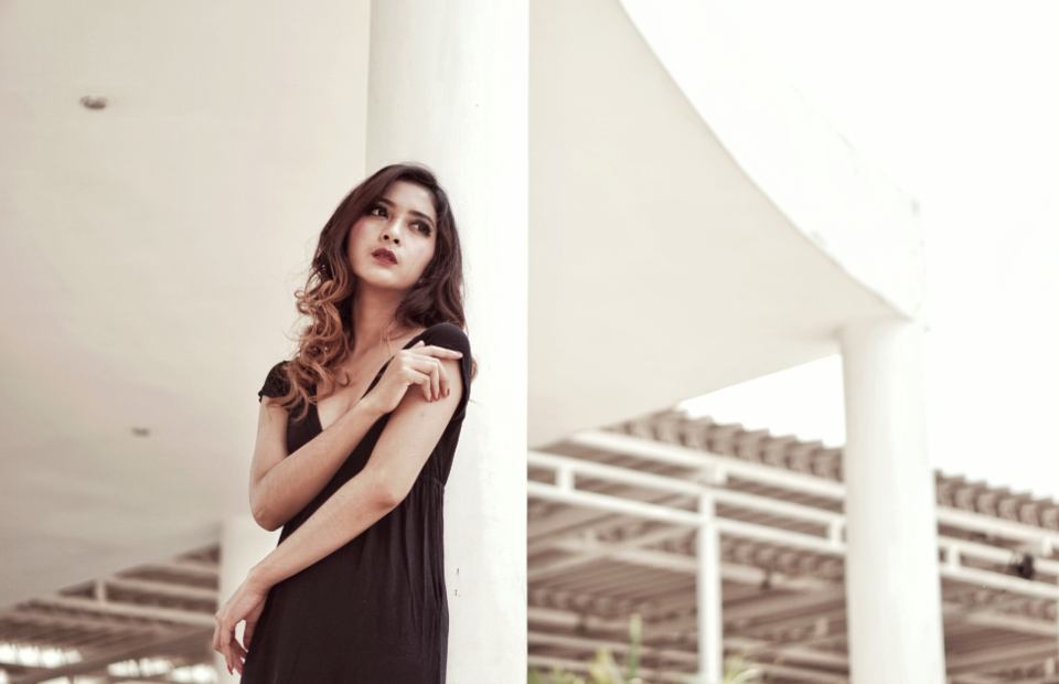 Model wearing a black dress in a bright architectural setting